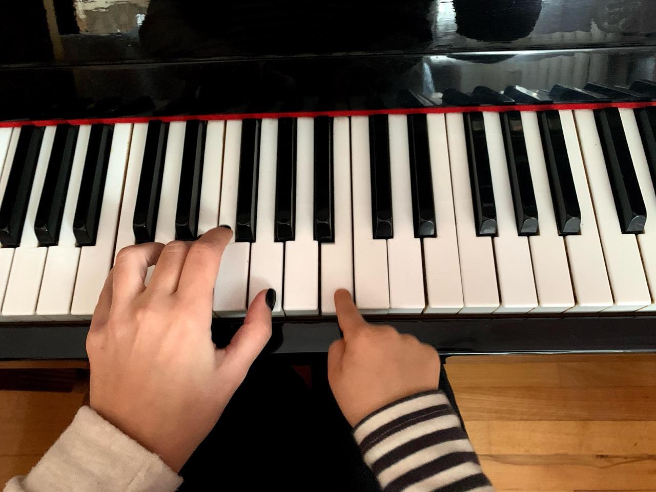 Hands playing piano keys during a lesson